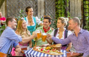 Gäste im Biergarten des Weltenburger am Dom stoßen mit Weltenburger Bier bei einer gemütlichen Brotzeit an