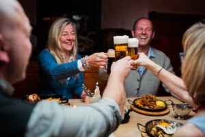 Mit dem weltberühmten Weltenburger Bier stoßen Gäste an einem reichlich gedeckten Tisch an