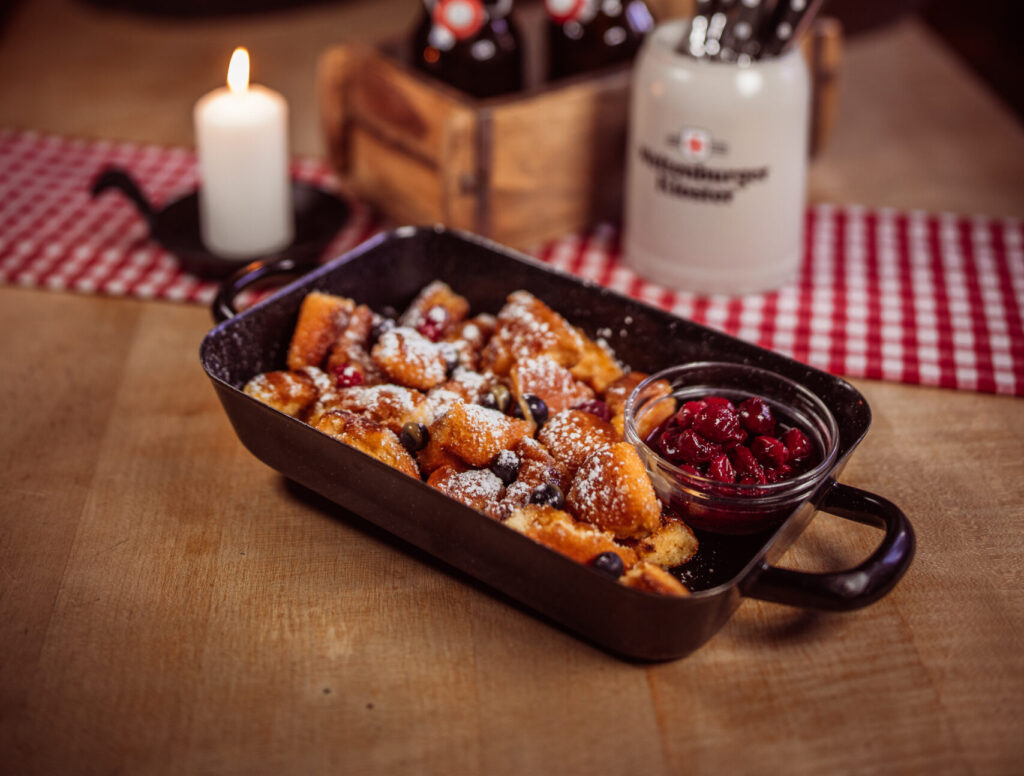 Appetitliches Foto eines Kaiserschmarrn. Der zerrupfte, fluffige Pfannkuchen ist goldbraun gebacken und mit Puderzucker bestäubt.