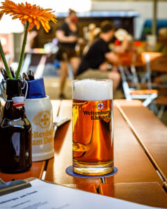 Ein Glas Anno 1050 steht auf dem Tisch im Biergarten des Weltenburger am Dom