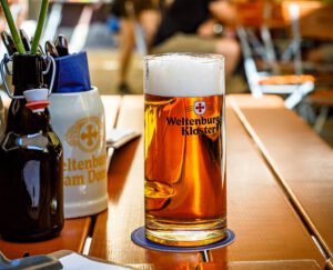 Ein Glas Anno 1050 steht auf dem Tisch im Biergarten des Weltenburger am Dom