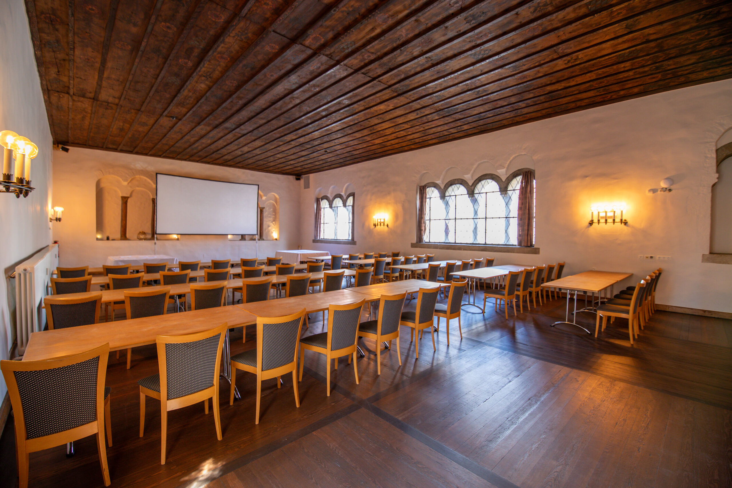 Der Herzogssaal wurde parlamentarisch bestuhlt um den perfekten Rahmen für ein Business Meeting zu geben. Vorne steht eine große Leinwand bereit für die Tagung