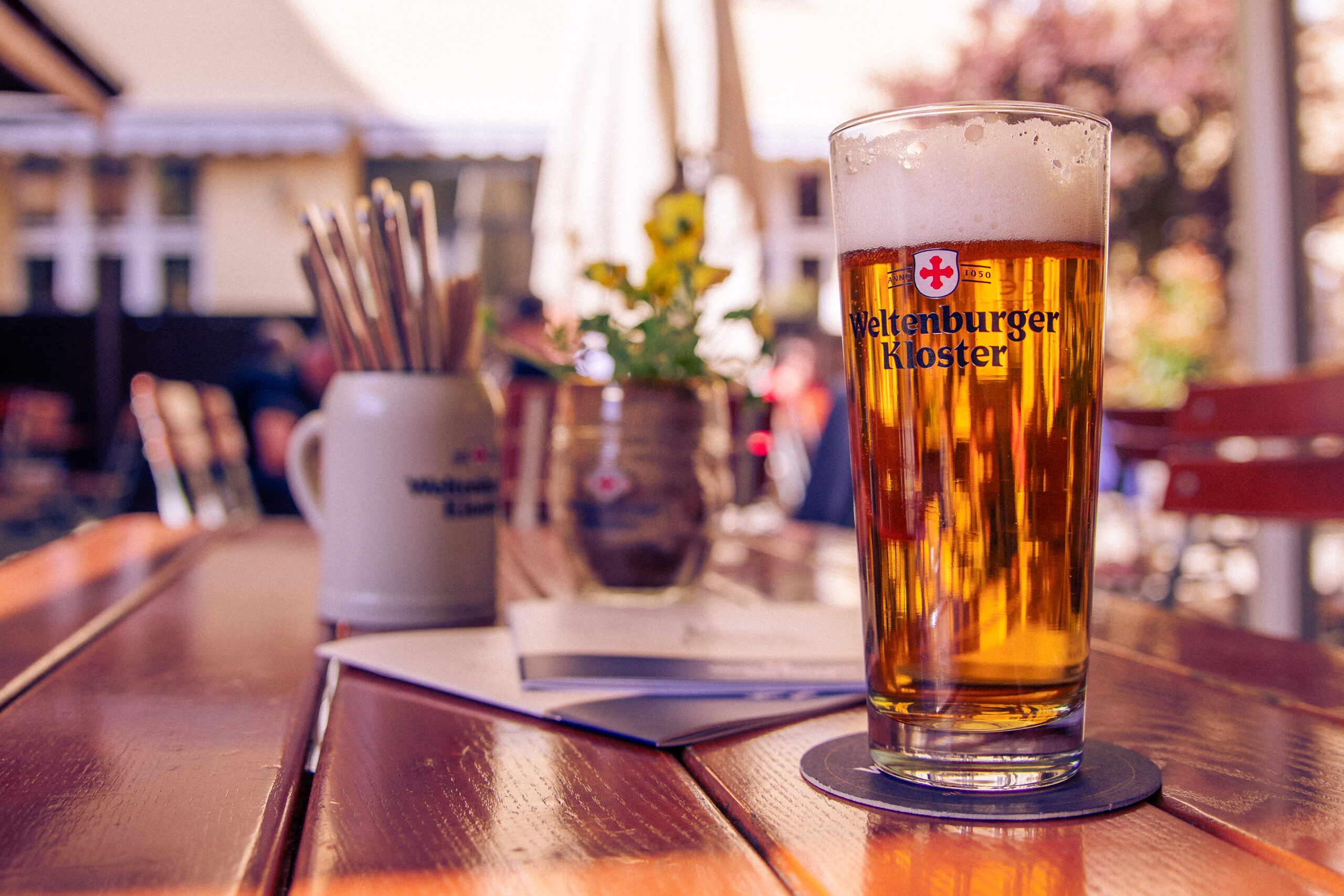 Ein Glas Anno 1050 steht auf dem Tisch im Biergarten des Weltenburger am Dom